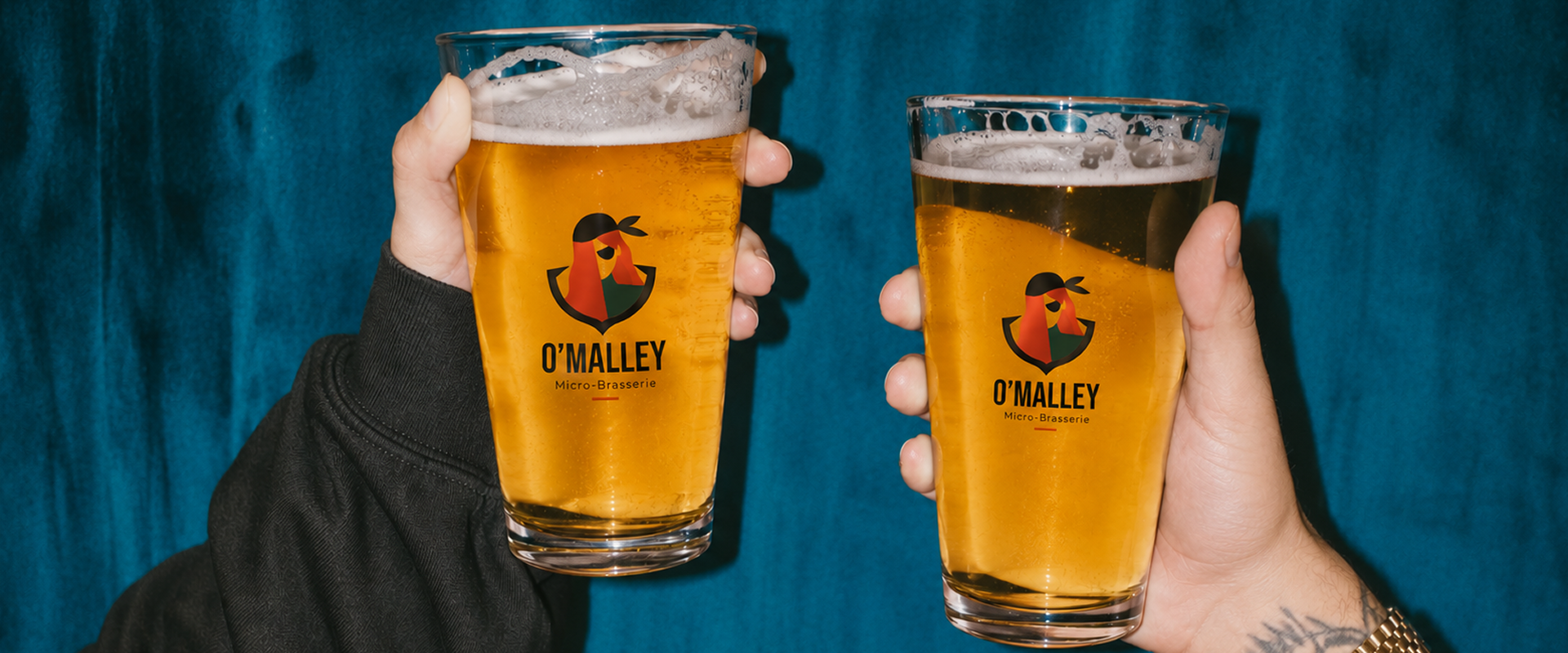 Deux personnes trinquent avec des pintes de bière O'Malley